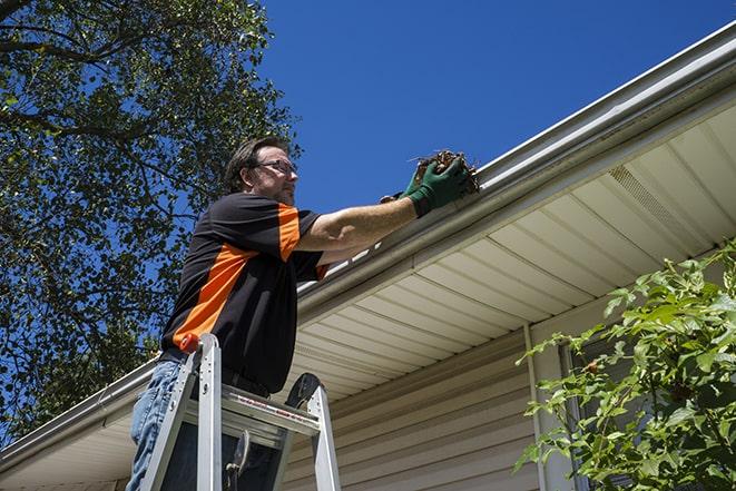 gutter repair specialist at work fixing a broken rain gutter in North Hills